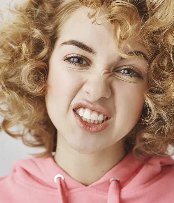 mujer mostrando los dientes con cara desagrado dientes apiñados